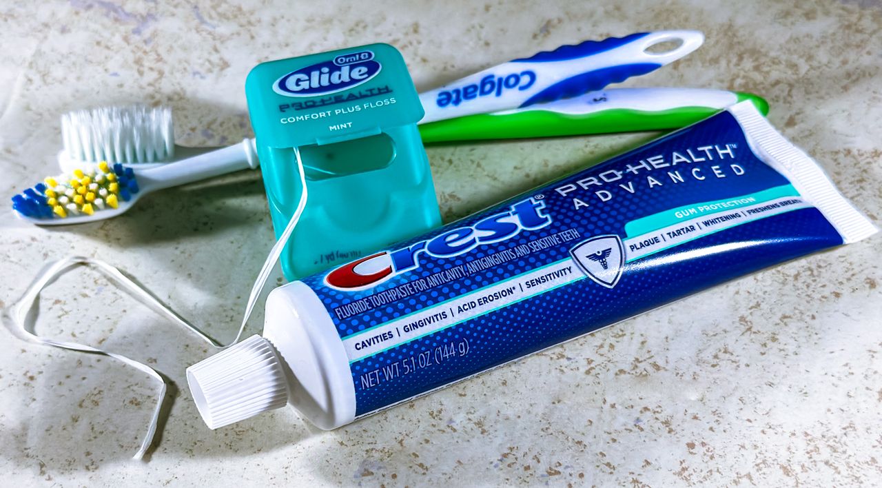 Close-up of dental care items including toothbrush, floss, and toothpaste for oral hygiene.