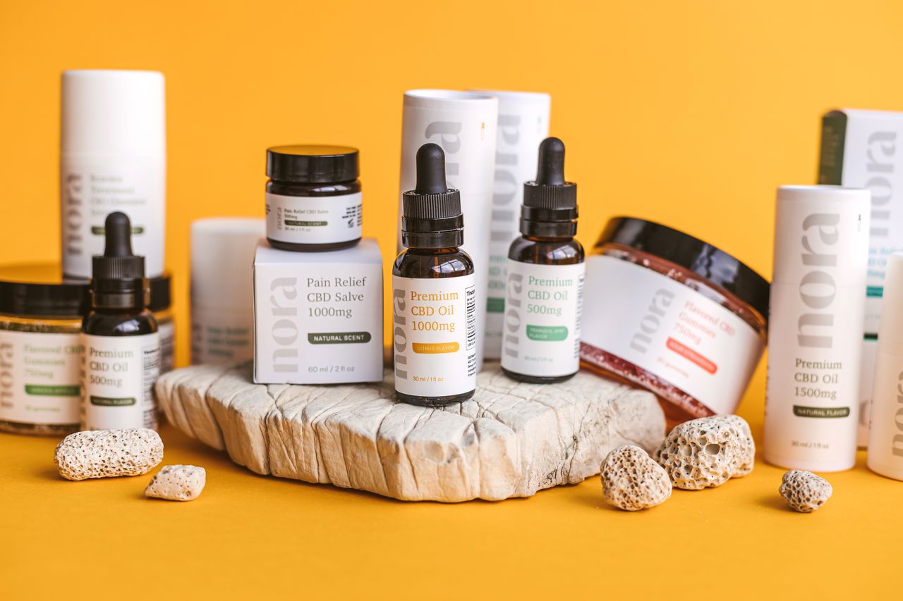 Various CBD bottles and containers arranged on a yellow backdrop for product photography.